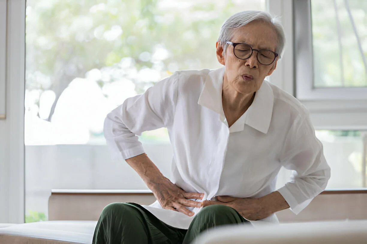 Elderly person holding their abdomen in pain, indicating acute pancreatitis