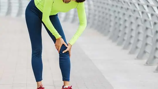 Person bending forward and holding their knee in pain, symbolizing a meniscus tear and stem cell treatment options
