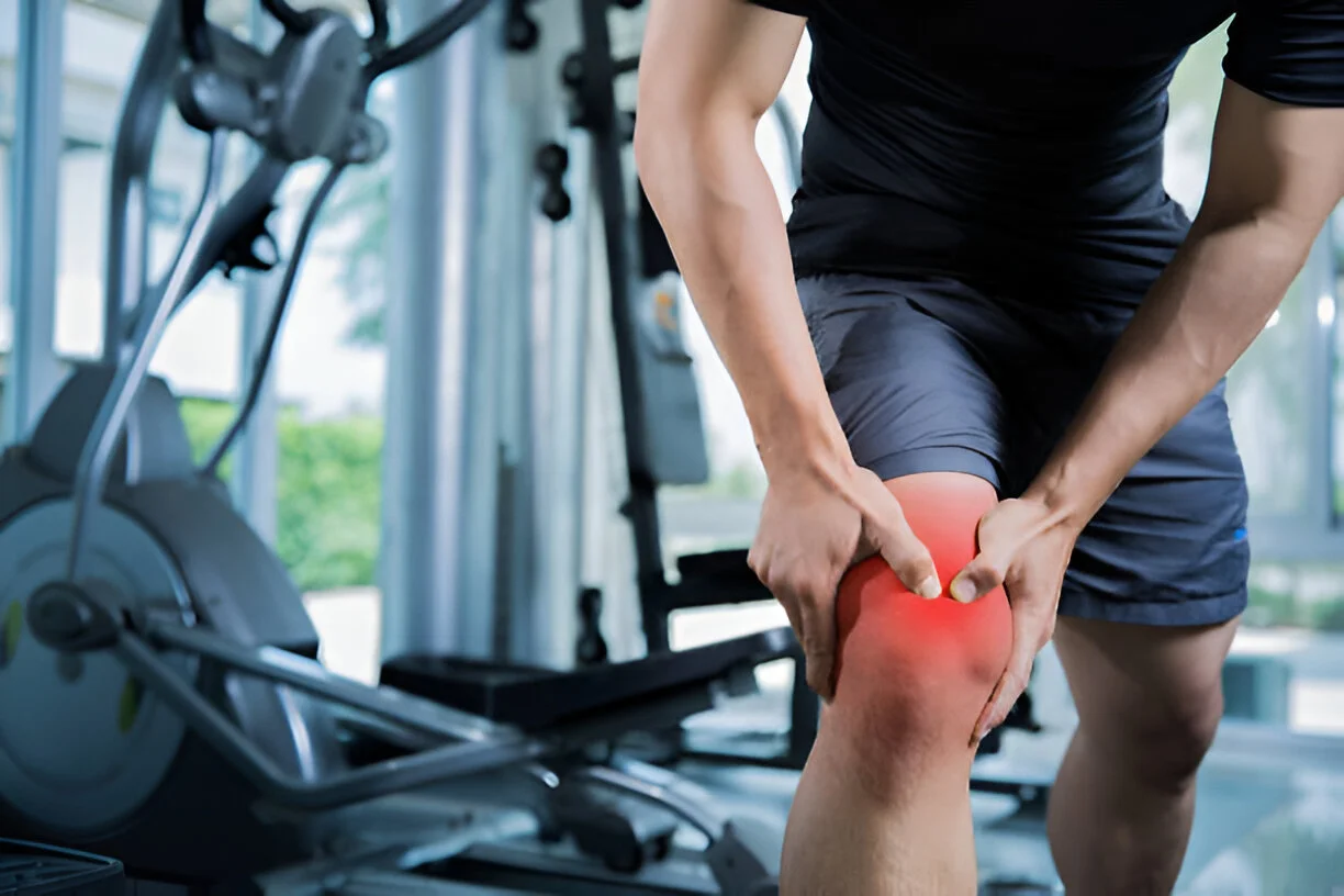 An athletic man holding his painful knee with a red highlight, representing a knee injury or joint pain treated by advanced stem cell therapy in Liberty Lake, WA.