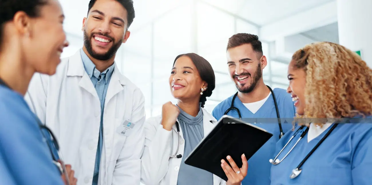 A diverse team of cheerful medical doctors and nurses discusses patient care, highlighting the collaborative and compassionate approach to stem cell therapy in Brooklyn.